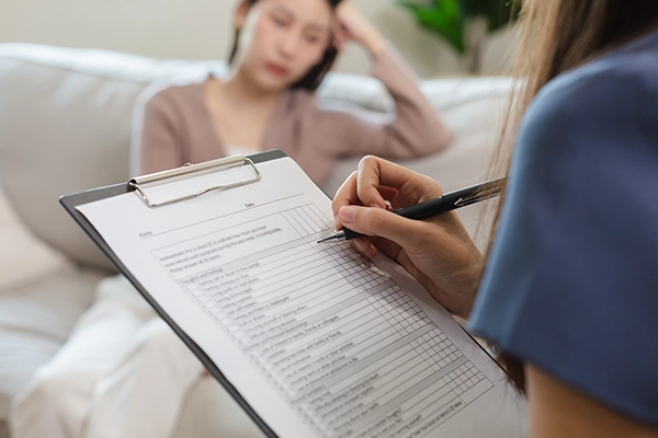psychiatrist-taking-notes-examining-female-patient Woman talking to a psychiatrist