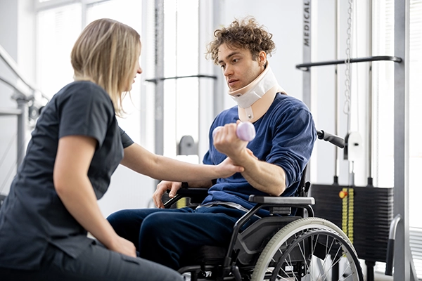 rehabilitation-specialist-with-injured-man-in-wheelchair Physical therapoist woking with a young man in a wheelchair
